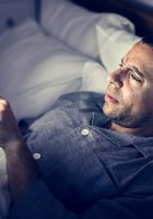 man-using-phone-on-a-bed-DE87TVN (1)