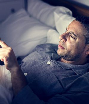 man-using-phone-on-a-bed-DE87TVN (1)